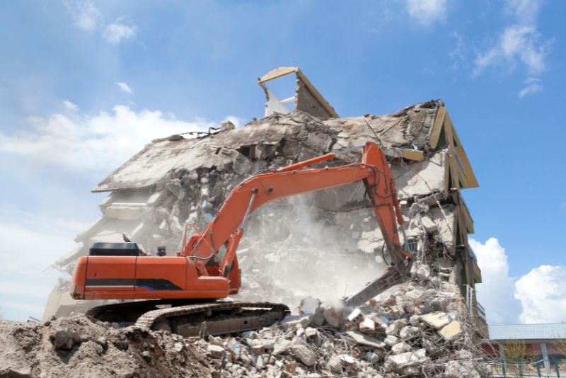 demolishing a building with a red excavator