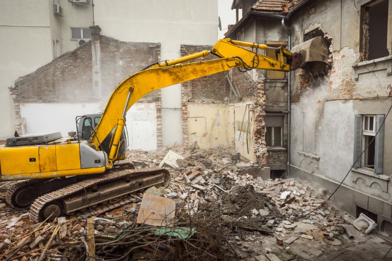 demolishing a building with a yellow excavator